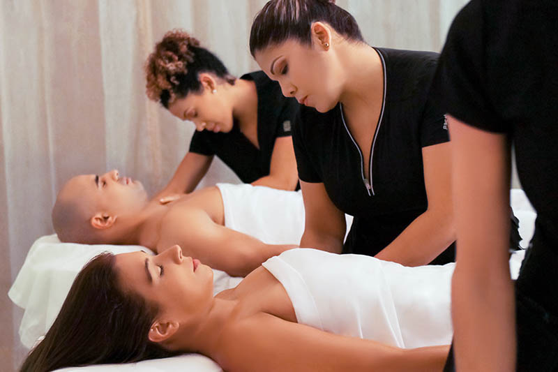Estudiantes que realizan masajes terapéuticos a clientes en el Salón de Celebrity