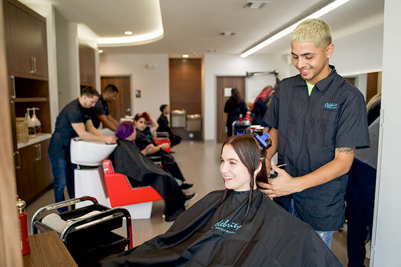 Un estudiante de Cosmetología de Celebrity lavando el cabello de un cliente en el salón de Celebrity.